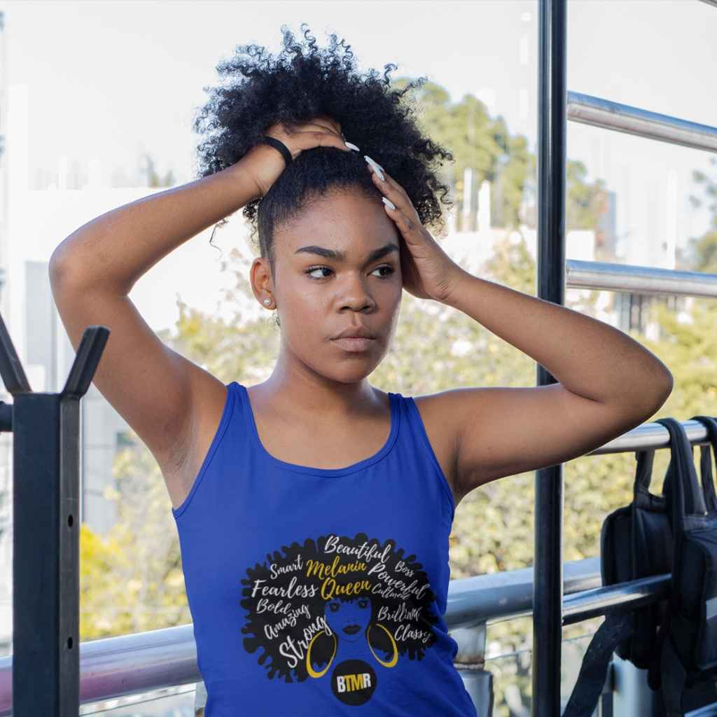 BlackToMyRoots Melanin Queen Royal Blue Tank top worn by a black young women in a gym. T Shirt features a design of a Black Woman silhouette with a large natural afro, which has positive words embedded in the afro. Underneath is the BlackToMyRoots logo - a solid black circle with the initials BTMR in the centre. Model is about to put her hair into a bunch. - 