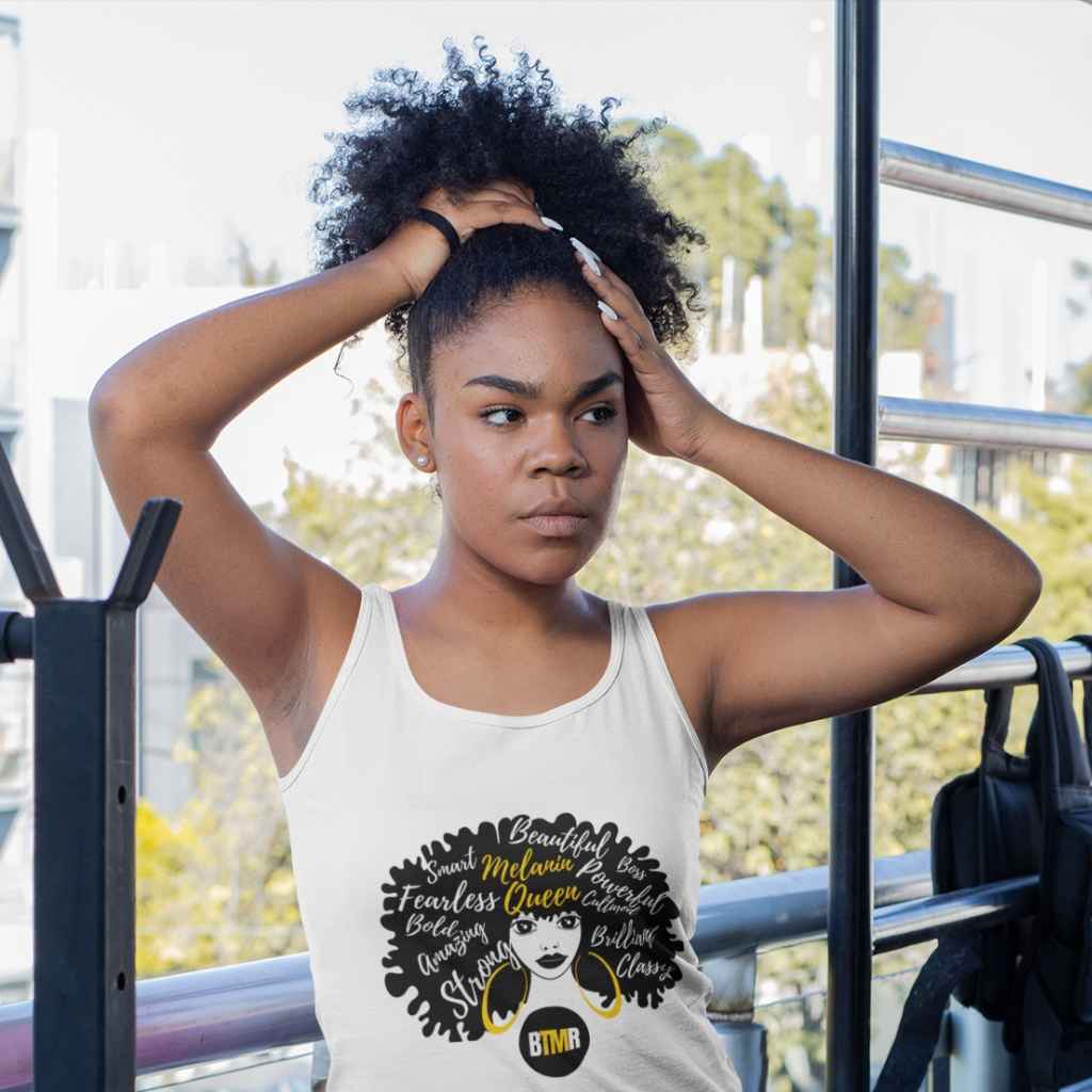 BlackToMyRoots Melanin Queen White Tank top worn by a black young women in a gym. T Shirt features a design of a Black Woman silhouette with a large natural afro, which has positive words embedded in the afro. Underneath is the BlackToMyRoots logo - a solid black circle with the initials BTMR in the centre. Model is about to put her hair into a bunch. - 