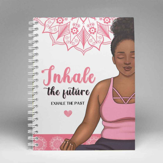 A5 spiral bound notebook, featuring a black woman sitting in a lotus pose - yoga. The Black woman is wearing a pink tank top. There is a pink mandala at the top of the notebook. The text says  Inhale the Future, Exhale the past.
